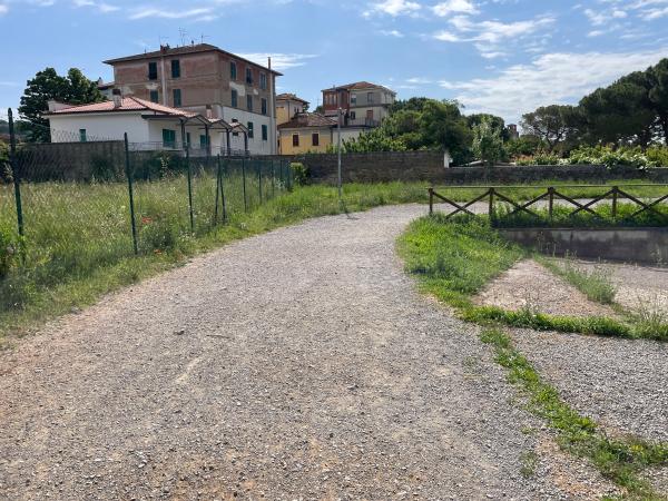 Ciclovia sterrata vicino alle case di Passignano. Recinzione metallica a sinistra, staccionata di legno a destra.